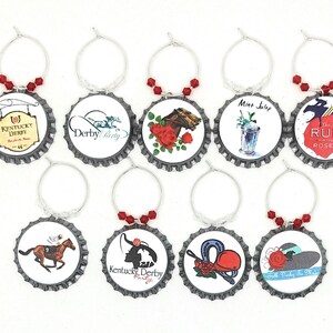 May include: Set of ten silver wine glass charms with red beads. Each charm features a different design inspired by the Kentucky Derby, including horses, roses, and hats. The charms are attached to silver rings.