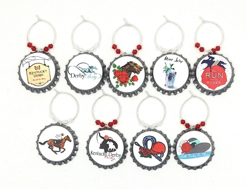 May include: Set of ten silver wine glass charms with red beads. Each charm features a different design inspired by the Kentucky Derby, including horses, roses, and hats. The charms are attached to silver rings.