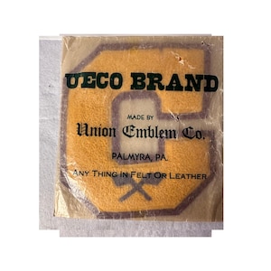 May include: A yellow felt letter C patch inside a clear plastic package. The packaging features the text UECO BRAND, MADE BY Union Emblem Co., PALMYRA, PA., and ANY THING IN FELT OR LEATHER printed in black ink over the yellow felt emblem.