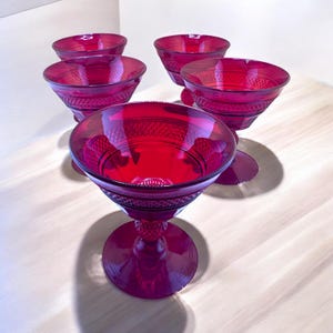 Könnte beinhalten: Satz von vier rubinroten Stielgläsern mit Diamantmuster. Die Gläser sind aus Glas und haben einen klaren Boden.