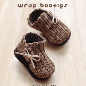 May include: A pair of brown crocheted baby booties with white ribbon ties. The booties have a wrap design and are made with a textured stitch.