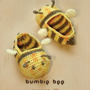 May include: A pair of crocheted bee-shaped slippers in yellow and brown. The slippers have black eyes and a striped pattern.