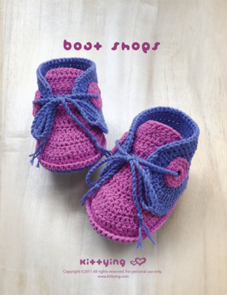 May include: A pair of purple and blue crocheted baby booties with a button detail. The booties are tied with a purple ribbon. The text "bost shops" and "Kit+ying" is visible in the image.