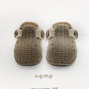 May include: A pair of brown and cream crocheted slippers with a button detail. The slippers are made with a hemp yarn and have a simple, minimalist design.