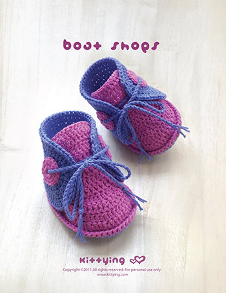 May include: A pair of purple and pink crocheted baby booties with a button detail. The booties are handmade and have a simple design.