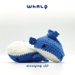 May include: Two crocheted whale plushies, one blue and white, the other all blue, with black eyes and a small mouth. The whales are lying on a white surface. The text "WHALE" is above the whales, and the text "kit+ying" is below them.
