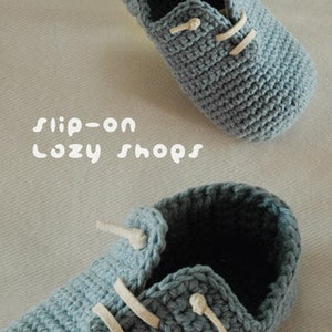 May include: A pair of crocheted baby shoes in a light blue color with white laces. The shoes are slip-on style and have a simple design. The text "slip-on Lazy Shops" is visible in the image.