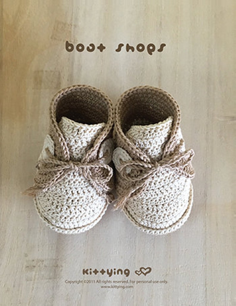 May include: A pair of beige and brown crocheted baby booties with a bow detail. The booties are labeled "boot shops" and "Kit+ying".
