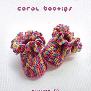 May include: A pair of colorful crocheted baby booties with a ruffled trim. The booties are made in a variety of colors, including pink, yellow, blue, and green. The booties are called "coral bootips" and are made by Kit+ying.