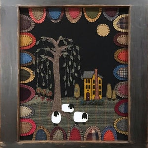 May include: A framed wool appliqué artwork depicting a night scene with a yellow house, a tree with hanging branches, and three white sheep in a field. The artwork is surrounded by a border of colorful circles.