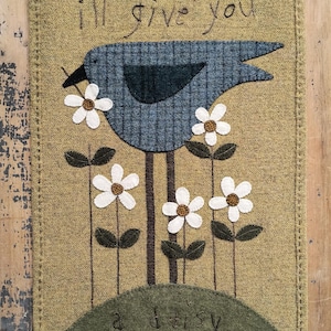May include: A green and brown felt wall hanging with a blue bird, white flowers, and the text "I'll give you a daisy day dear".
