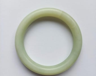 Pode incluir: Um bracelete de jade verde claro. O bracelete é liso e polido.