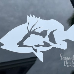 May include: White silhouette of a fish with a large dorsal fin on a black background. The fish is facing the right side of the image. The text "Samantha Dominis Designs" is in the lower right corner of the image.