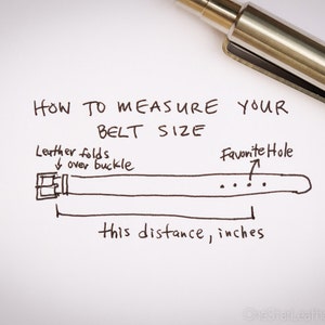 May include: Handwritten instructions on how to measure your belt size in inches. The illustration shows a belt with a buckle and multiple holes. The text indicates to measure the distance from the buckle to the hole you use most often.