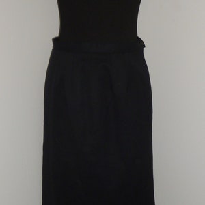 Pode incluir: Uma saia preta até o joelho com um design simples e um fecho de botão na cintura.