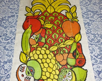 Pode incluir: Uma toalha de cozinha vintage com uma ilustração colorida de frutas, incluindo um abacaxi, maçãs, uvas, cerejas, uma lima e uma banana. A toalha é branca com uma textura de linho e tem a assinatura "Gengo Briand" no canto inferior direito.