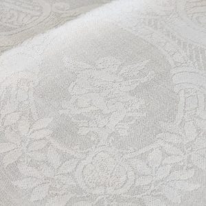 Op de afbeelding: Witte stof met een subtiel reli&euml;f bloemenpatroon. De stof voelt zacht en textuurrijk aan.