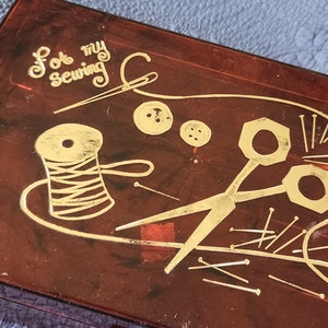 May include: A brown plastic sewing box with gold lettering that says "For my sewing". The box has a design of a spool of thread, scissors, buttons, and needles.