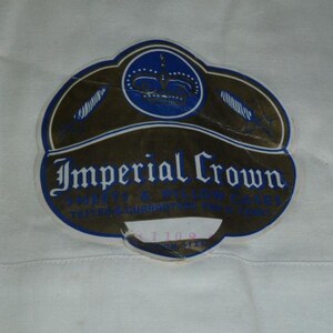 May include: A vintage Imperial Crown label, featuring a blue and gold design. The label displays the words "Imperial Crown" in an ornate font, with a crown emblem at the top. The label shows signs of wear.