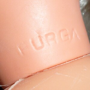 Puede incluir: Primer plano del cuello de una mu&ntilde;eca con la palabra "HURGA" en relieve en la piel.
