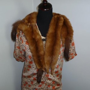 May include: Vintage dress with a floral pattern in cream and orange, paired with a brown fur collar. The dress has short sleeves and is displayed on a mannequin.