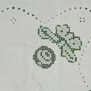 May include: White fabric with a green embroidered design of a flower and a leaf.
