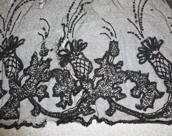 May include: Black beaded lace trim featuring a design of stylised thistles. The trim is made of black beads sewn onto a sheer black fabric.