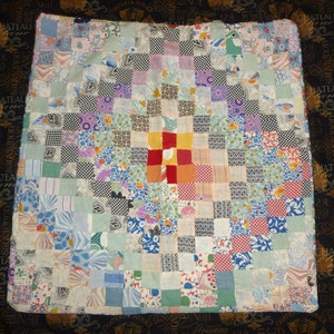 May include: A patchwork quilt with a variety of colorful fabrics in a checkered pattern. The center of the quilt features a red, orange, and white square.