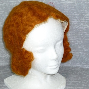May include: A brown felt hat with a scalloped edge. The hat is on a white styrofoam head.