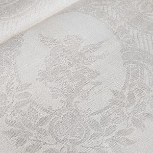 Op de afbeelding: Witte stof met een subtiel reli&euml;fpatroon van bladeren en bloemen. De stof heeft een zachte, textuur.