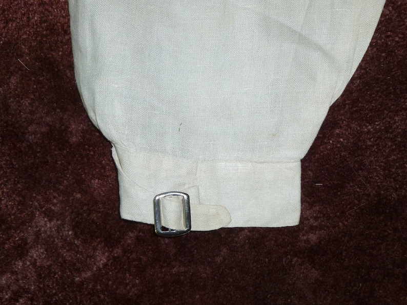 May include: A white linen shirt cuff with a silver metal buckle.