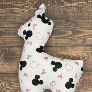 Puede incluir: Juguete de peluche blanco con forma de llama con orejas de Mickey Mouse negras y corazones impresos.