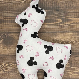 Puede incluir: Juguete de peluche blanco con forma de llama con un estampado de Mickey Mouse en blanco y negro y corazones rosas.