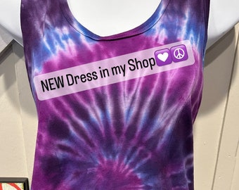 May include: Purple and blue tie-dye sleeveless dress with a scoop neck. The dress has a swirl pattern and the text "NEW Dress in my Shop ❤️☮️" is printed on the front.