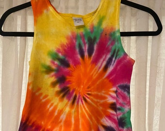 May include: A sleeveless tie-dye tank top in shades of yellow, orange, pink, green, and purple. The shirt has a swirling tie-dye pattern.