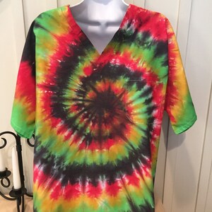 May include: A tie-dye scrub top with a v-neck and a pocket. The shirt is a swirl of red, yellow, green, and black.