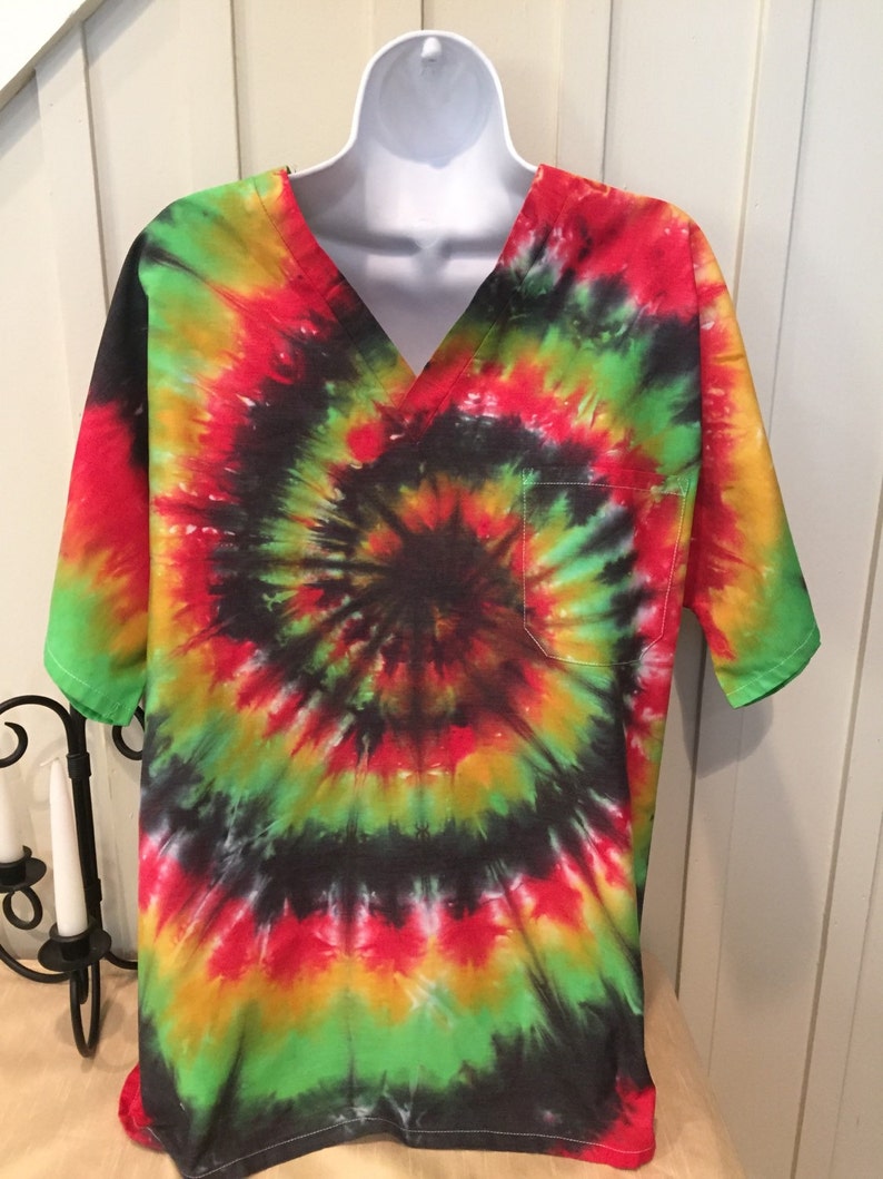 May include: A tie-dye scrub top with a v-neck and a pocket. The shirt is a swirl of red, yellow, green, and black.