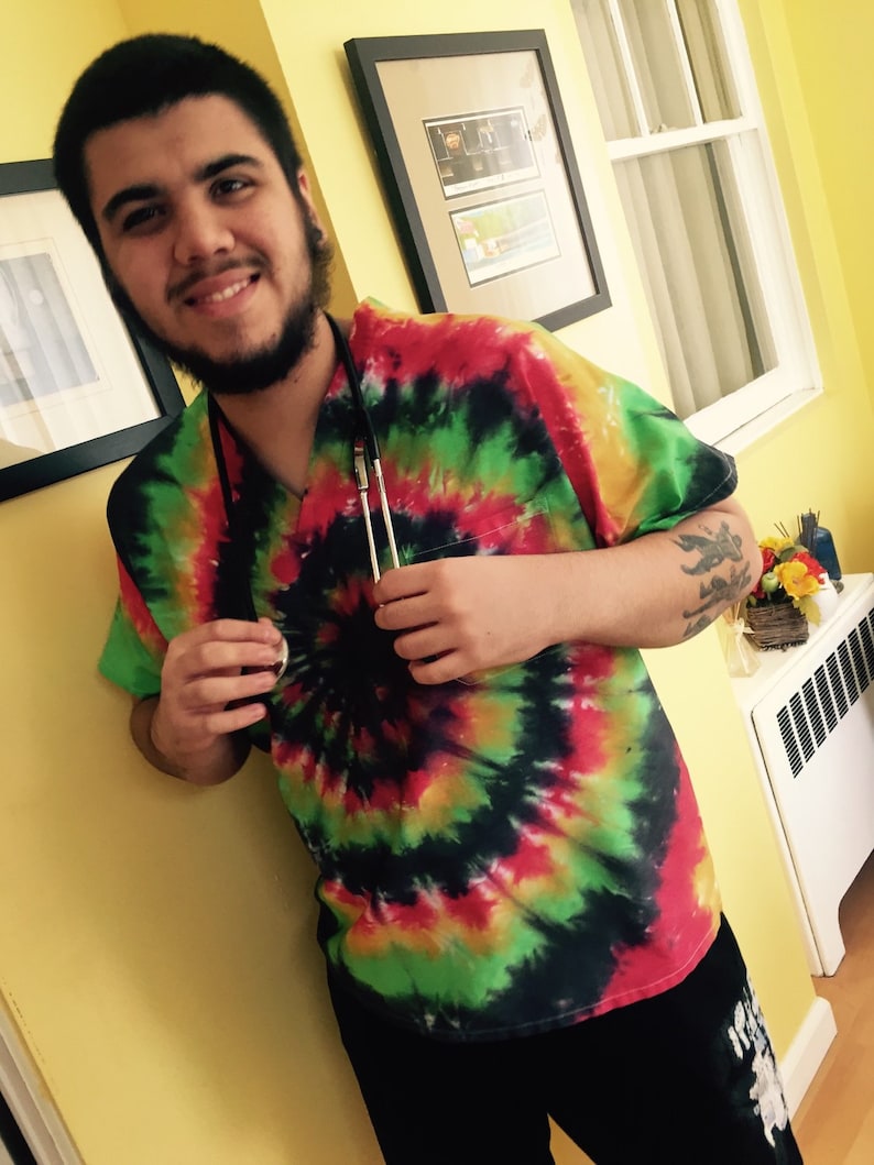 May include: A person wearing a tie-dye shirt with a stethoscope around their neck. The shirt is a mix of red, green, yellow, and black.