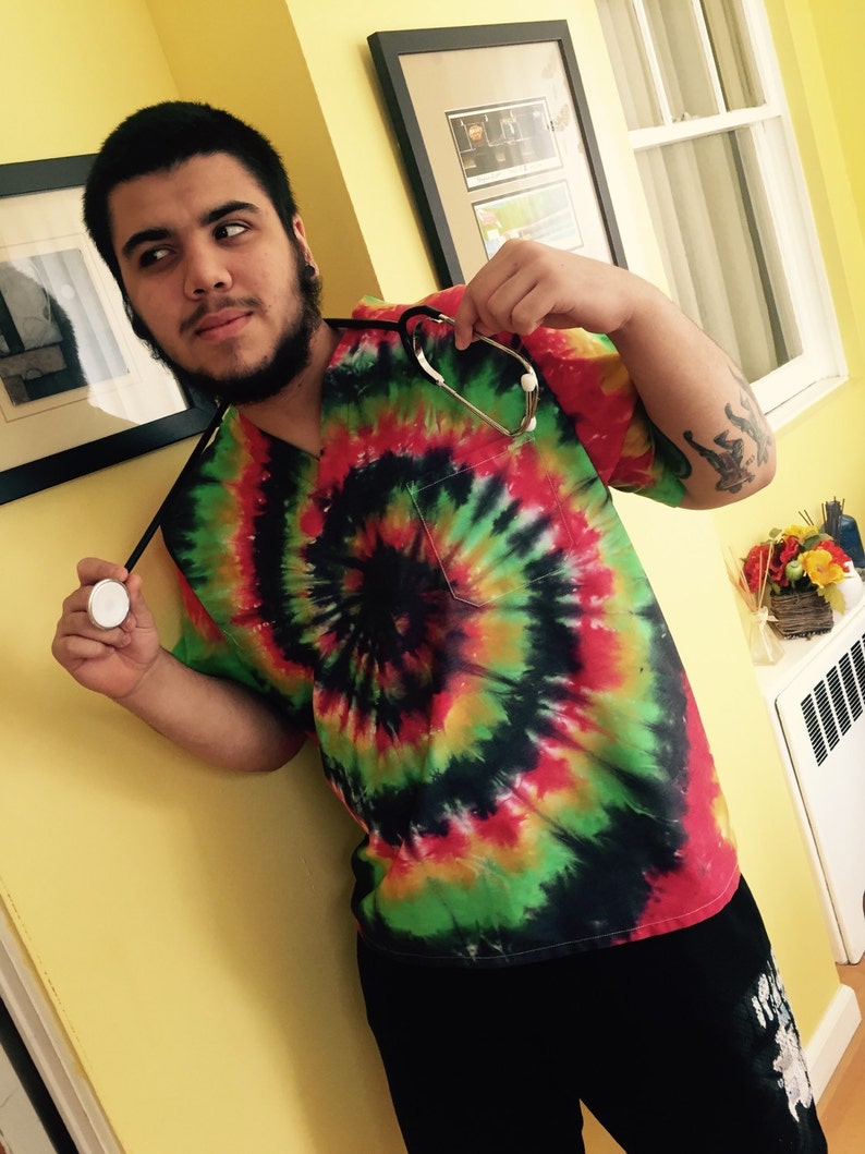 May include: A person wearing a tie-dye shirt with a stethoscope around their neck. The shirt has a red, green, yellow, and black swirl pattern.