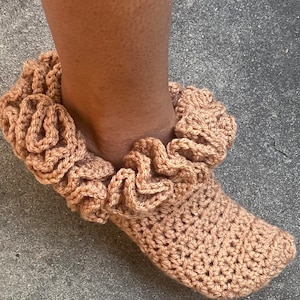 May include: A pair of brown crocheted slippers with a ruffled trim around the ankle.