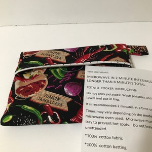 May include: A black fabric pouch with a white polka dot trim and a colourful print of food and the words "Jumpin' Jambalaya". The pouch has instructions for using it as a potato cooker in the microwave. The instructions say to microwave in 2 minute intervals for a total of 8 minutes. The pouch is made of 100% cotton fabric, batting, and thread.