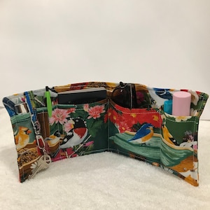 Könnte beinhalten: Ein Organizer mit mehreren Fächern mit einem Vogel- und Blumenmuster. Der Organizer hat mehrere Taschen und ist geöffnet, um das Innere zu zeigen. Der Organizer ist aus Stoff und hat einen Reißverschluss.