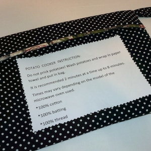 May include: A black and white polka dot fabric pouch with a white paper instruction tag. The tag reads "POTATO COOKER INSTRUCTION: Do not prick potatoes! Wash potatoes and wrap in paper towel and put in bag. It is recommended 2 minutes at a time up to 8 minutes. Times may vary depending on the model of the microwave oven used. *100% cotton *100% batting *100% thread"