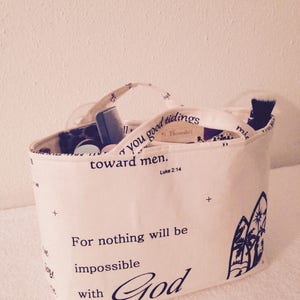May include: A white canvas tote bag with black text and a black and white illustration of a palm tree. The text reads "For nothing will be impossible with God" and "good tidings toward men. St. Benedict Luke 2:14".