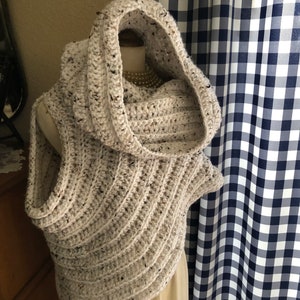 May include: A white crocheted cowl with a hood. The cowl has a speckled pattern and is made with a chunky yarn.
