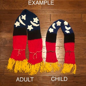 May include: Two crocheted scarves with a blue, black, and red striped pattern and white crescent moon and star designs. The larger scarf is labeled "Adult" and the smaller scarf is labeled "Child".