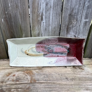 Puede incluir: Una bandeja rectangular de cerámica con un esmalte blanco y un diseño abstracto rojo, azul y blanco.