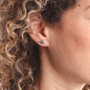 May include: A pair of gold leaf stud earrings. The earrings are small and delicate, and they feature a realistic leaf design.