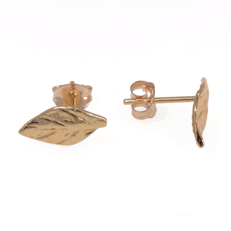 May include: A pair of gold leaf stud earrings. The earrings are made of 14k gold and feature a delicate leaf design.