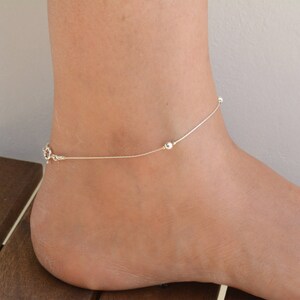 May include: A delicate silver anklet with small round beads. The anklet is thin and has a simple design.